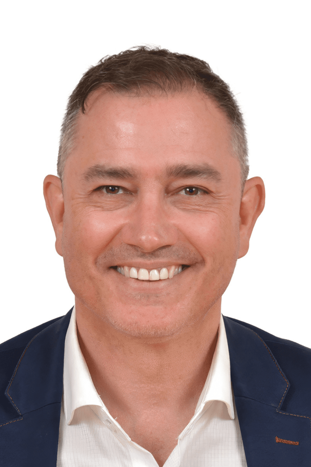 Portrait professionnel de Stéphane Lepage, homme souriant aux cheveux courts châtains grisonnants, portant une chemise blanche et un veston bleu marine, sur fond blanc.