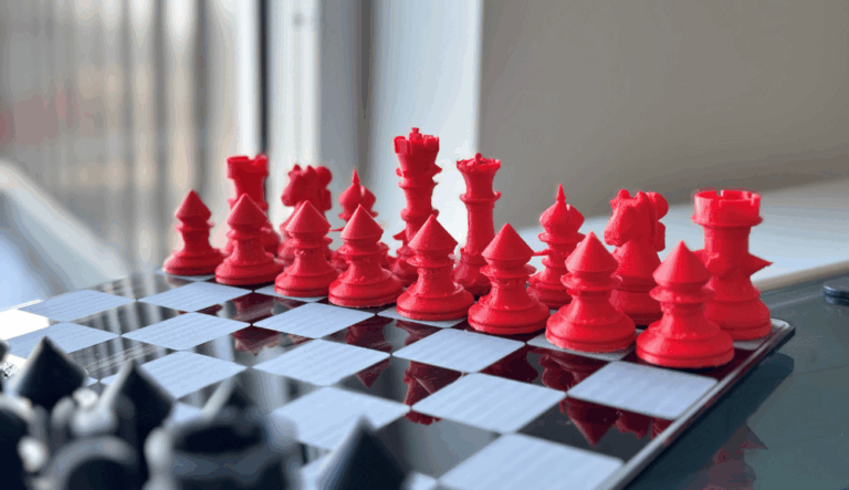 Ensemble de pièces d’échecs rouges, au design géométrique, disposées sur un échiquier noir et blanc, vues en gros plan.