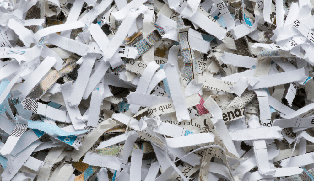 Papier déchiqueté composé de bandes blanches et imprimées entremêlées.