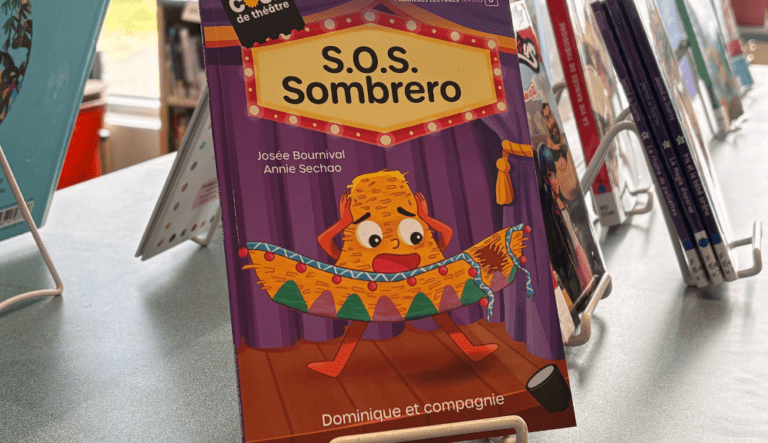 Livre jeunesse intitulé S.O.S. Sombrero exposé sur un présentoir, avec une couverture illustrée montrant un sombrero paniqué sur une scène de théâtre.