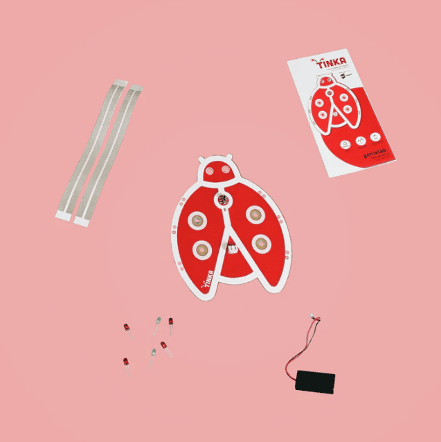 Composantes d’un projet électronique en forme de coccinelle comprenant une carte rouge, des DEL, un boîtier de piles et un emballage.